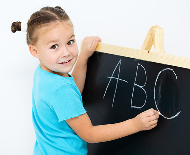 Little girl writing ABC with chalk