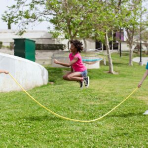 Children enjoying a sunny day playing jump rope outdoors in a park.